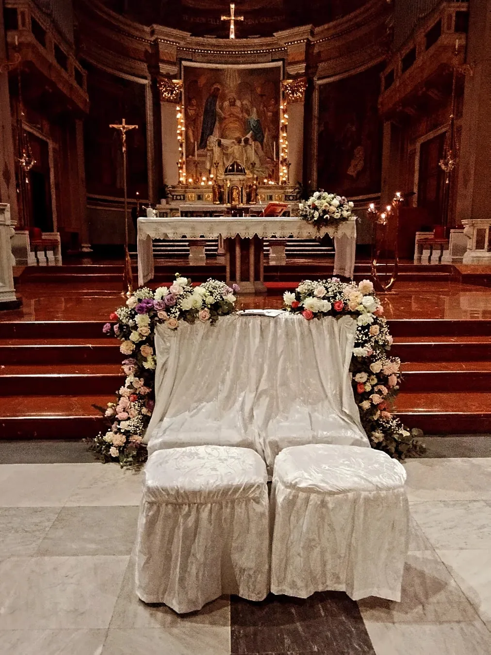 Addobbo floreale dell'altare in chiesa con rose bianche e rosa davanti ai posti degli sposi