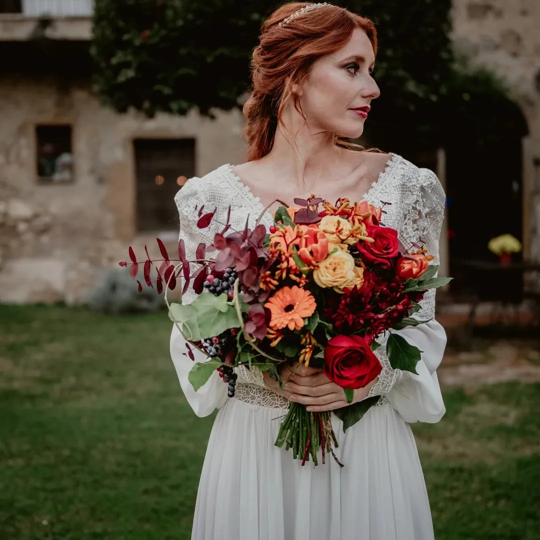 Sposa con bouquet autunnale di rose rosse, gerbere arancio e foglie bordeaux
